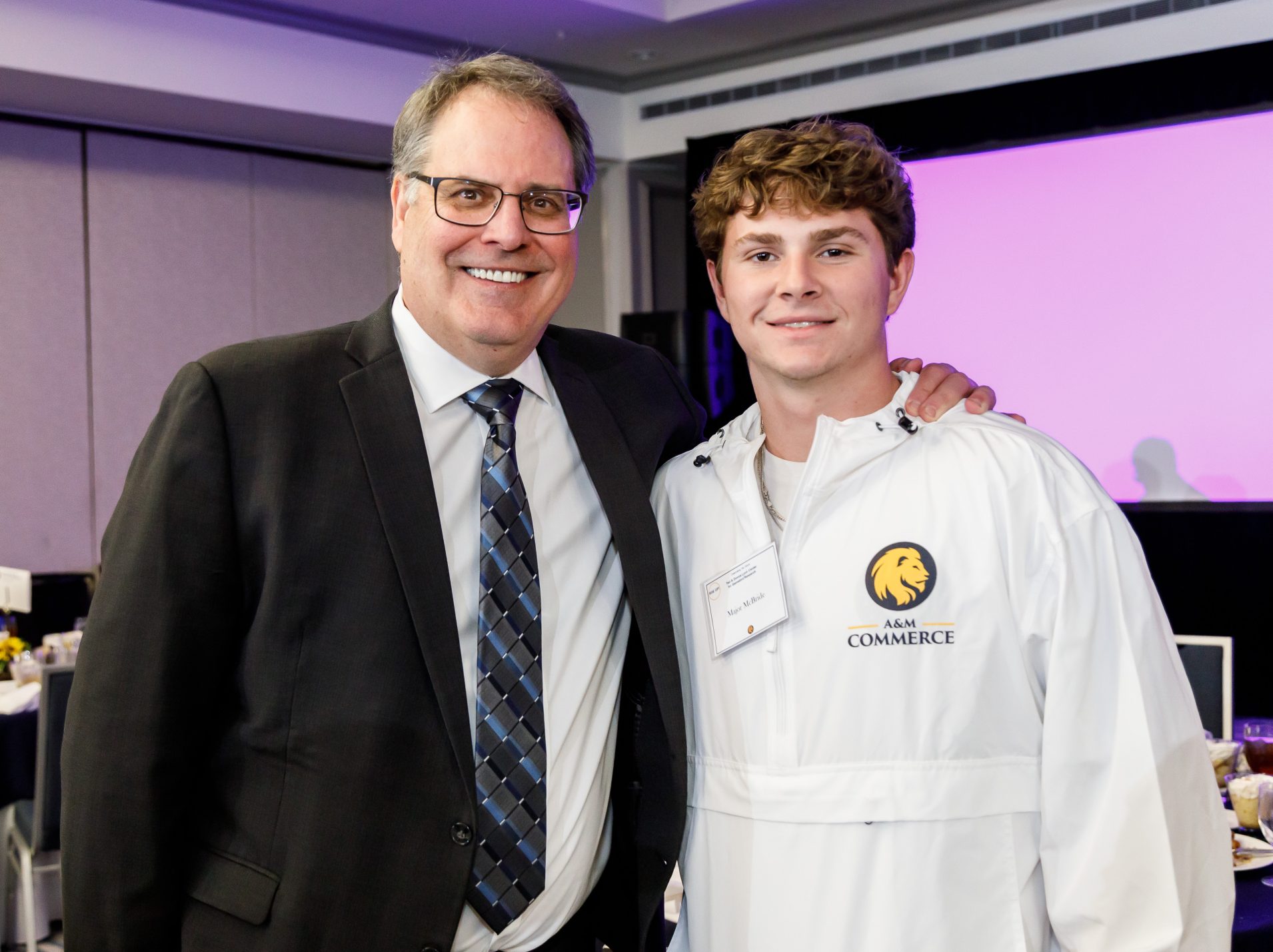 Dr. Mark Rudin (left) and student Major McBride (right) face the camera and smile. The man on the left has his hand on the shoulder of the man on the right.
