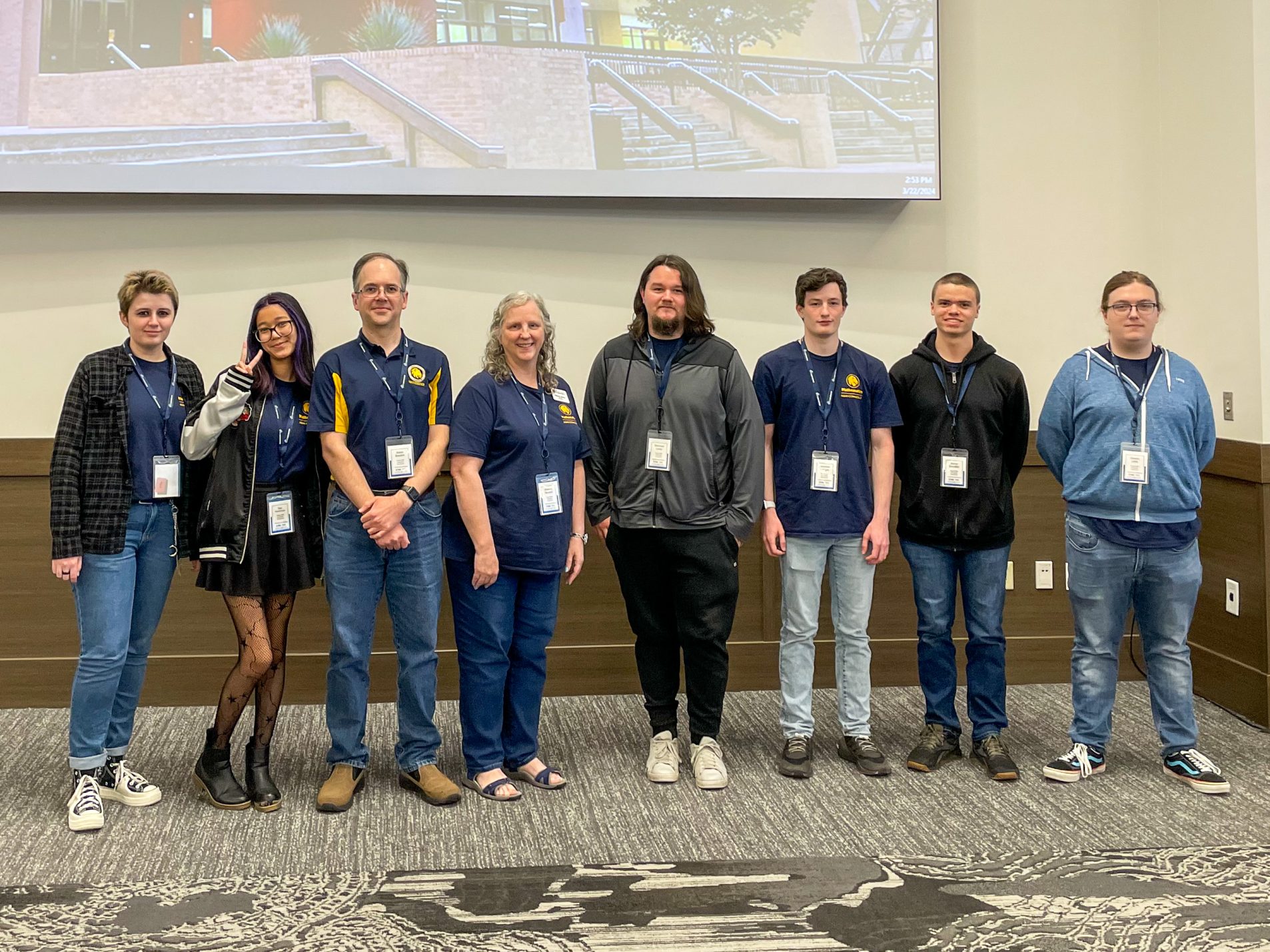 A group of students and faculty stand side by side for a photo.