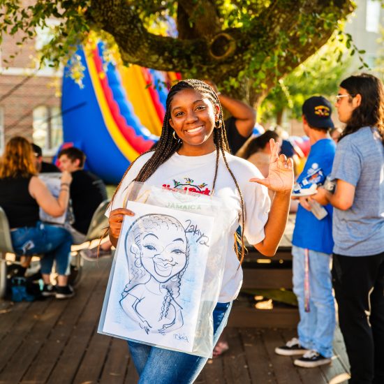 Female student holding a caricature drawing of herself.