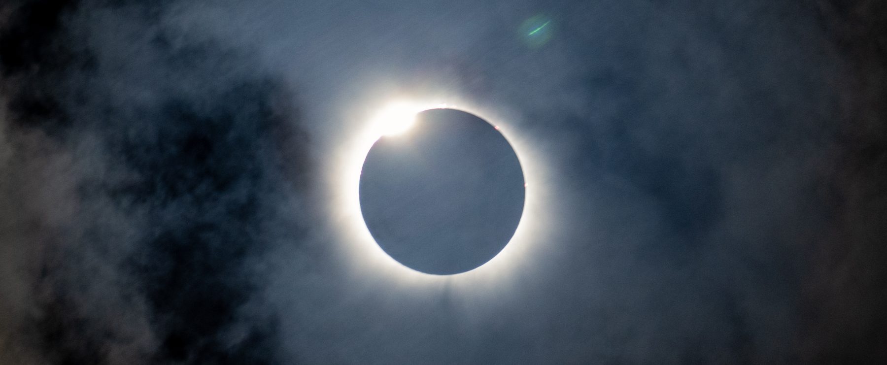 A photo of a total solar eclipse viewable through a thin layer of clouds.