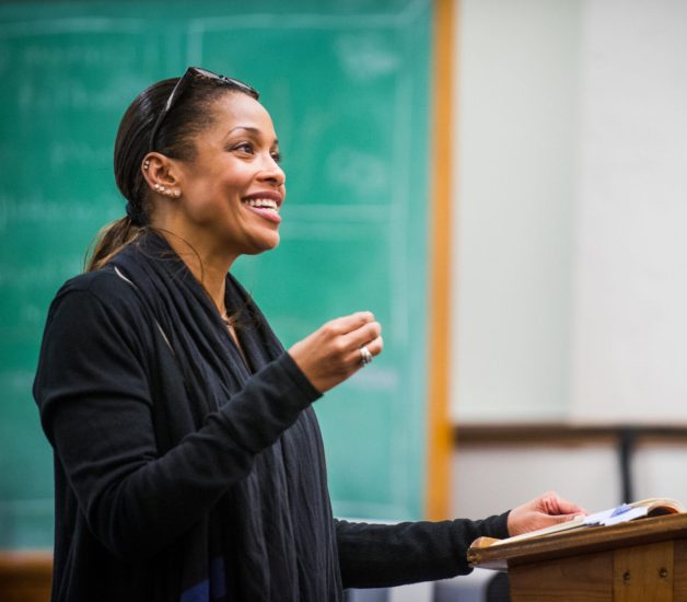 A female professor lecturing in a classroom.
