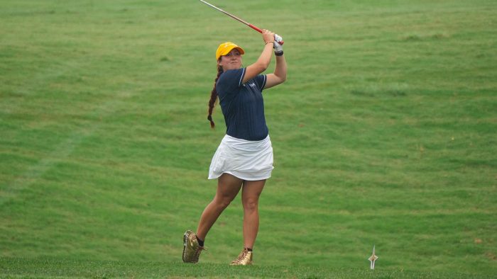 Golfer swings a club on a golf course.