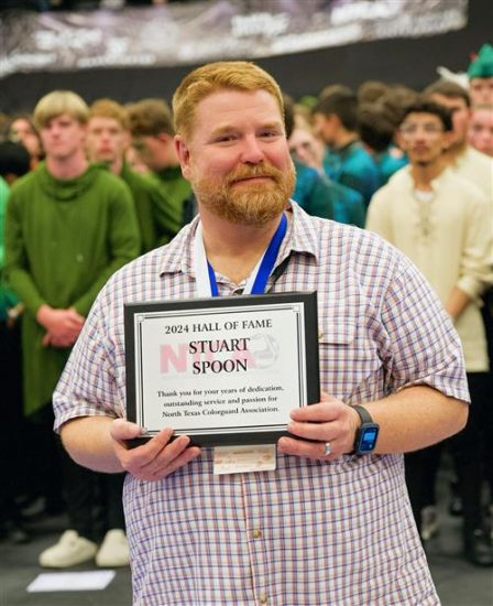 A person posing with an award plaque.