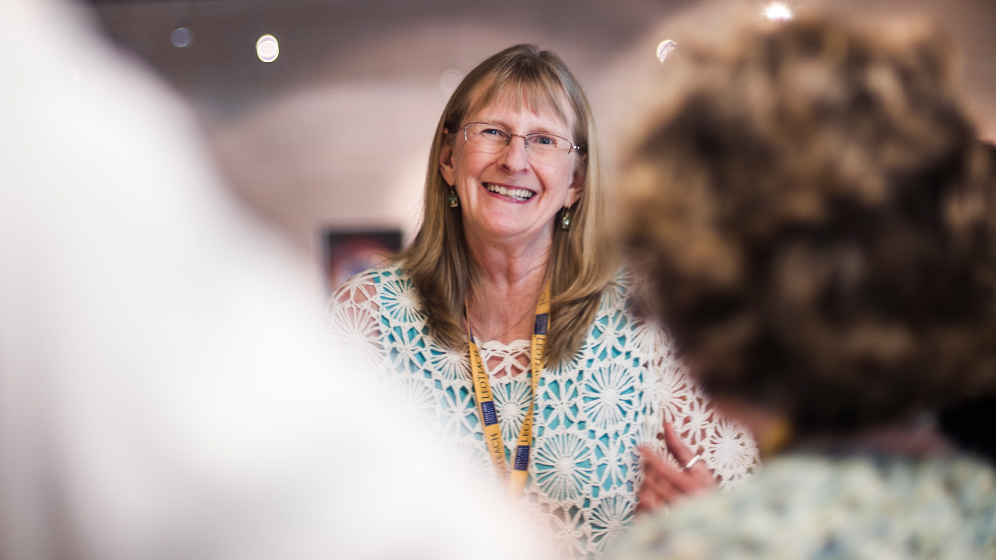 Dr. Kit Blount faces the viewer, positioned between two people in the foreground facing her.