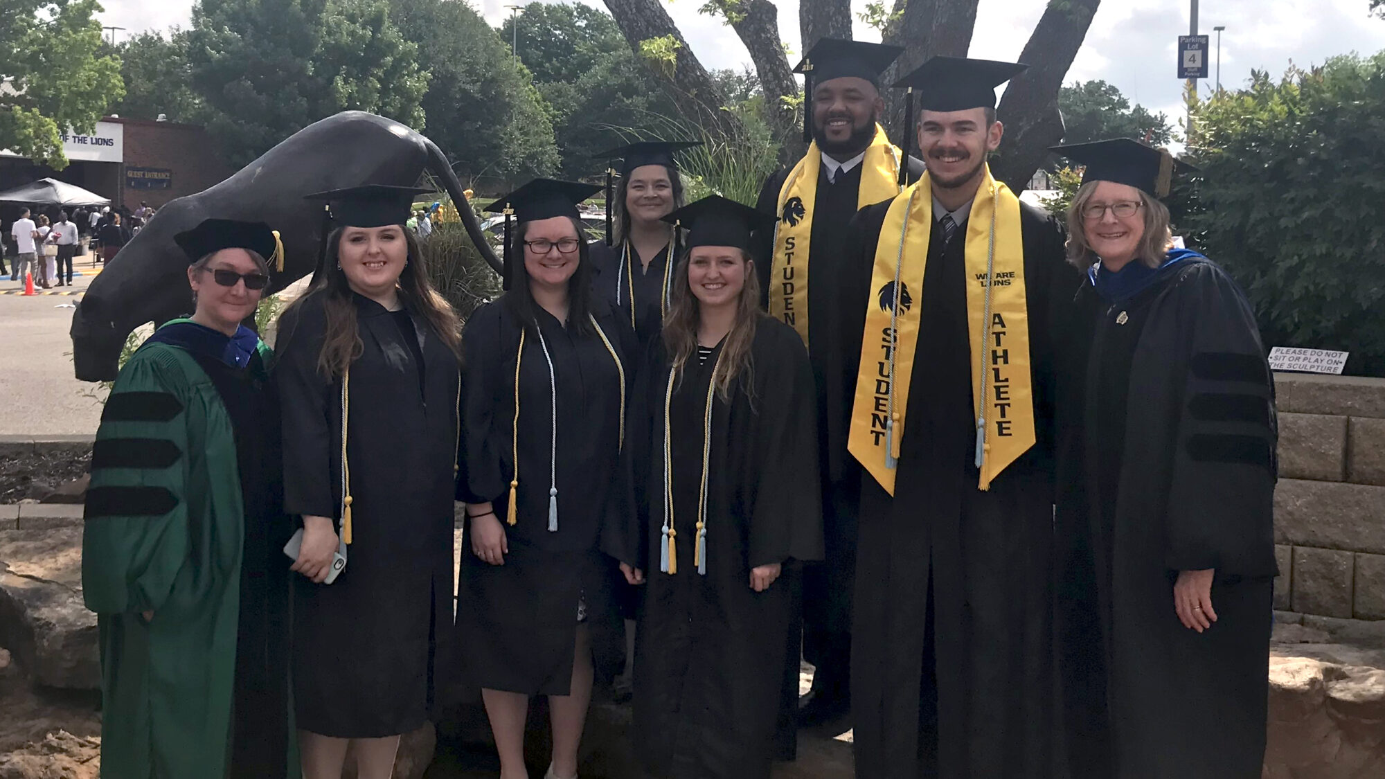 A group of faculty and graduates stand outside for a photo.