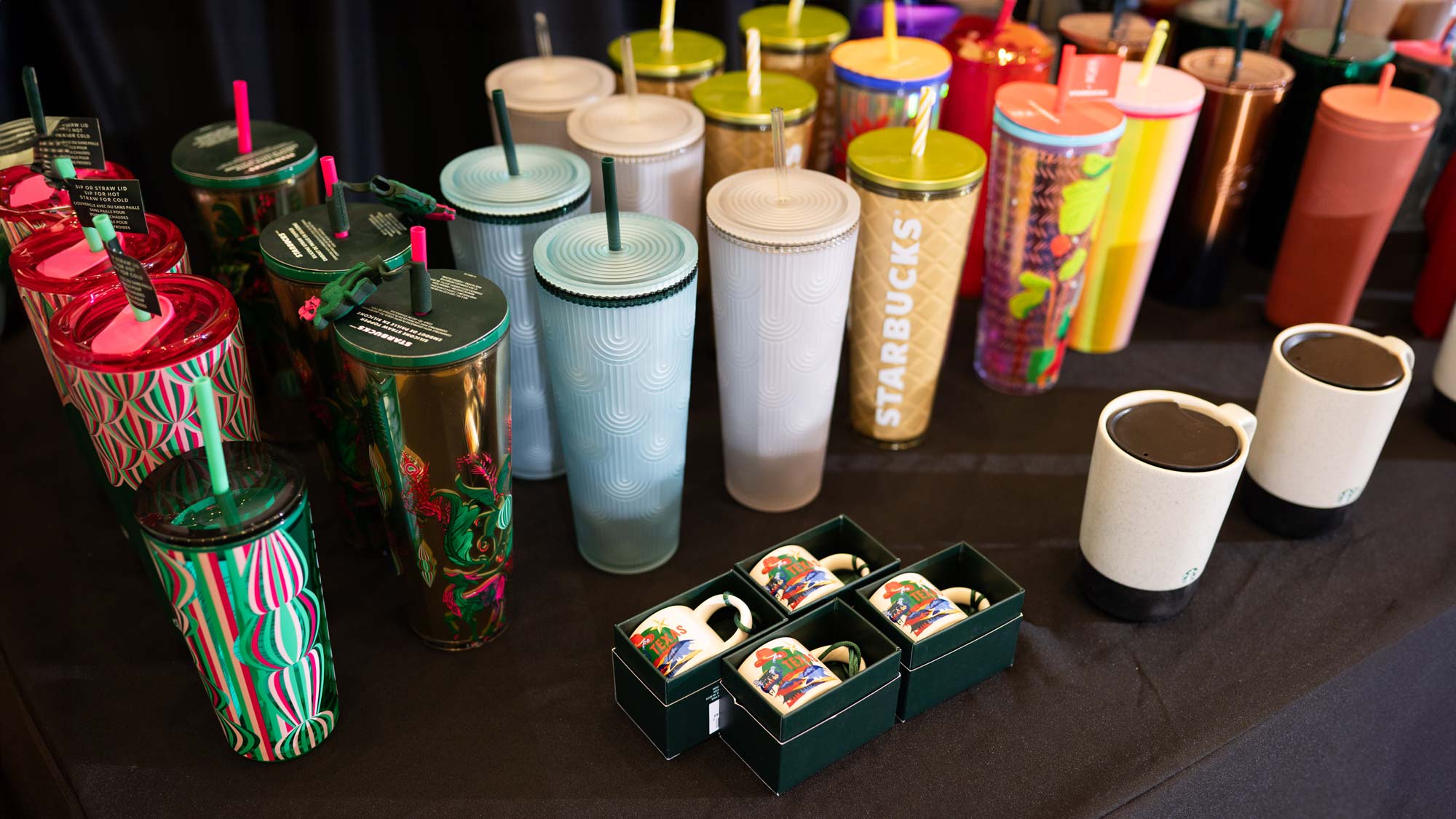 A collection of colorful cups, most with lids and straws, sits on a table.